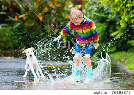 Kids in puddle in autumn rain. Waterproof wear 76198875