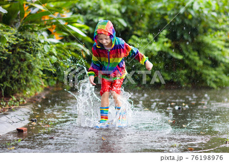 Kids in puddle in autumn rain. Waterproof wear Kids in puddle in autumn rain. Waterproof wear 76198976