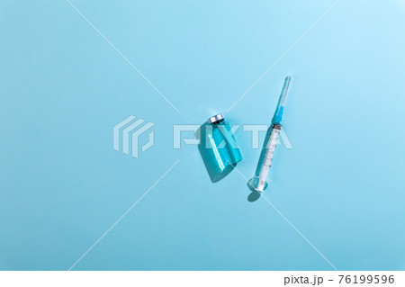 Glass vaccine ampoules, bottle, syringe, needle, blue background 76199596