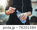 Female athlete opening the plastic cap of mineral water bottle 76201384
