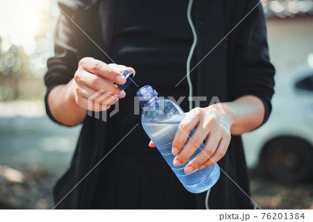 Female athlete opening the plastic cap of mineral water bottle 76201384