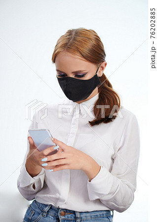 Portrait of young girl in mask using smartphone Portrait of young girl in mask using smartphone 76202885