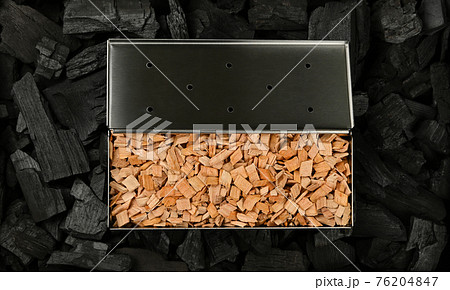 Metal smoker box with wood chips on charcoal 76204847