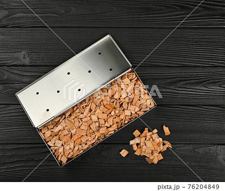 Metal smoker box with wood chips on table 76204849