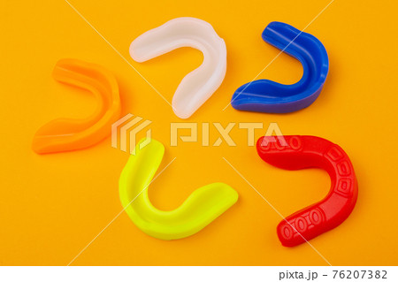 five boxing mouthguards of different colors lie on a yellow background five boxing mouthguards of different colors lie on a yellow background 76207382