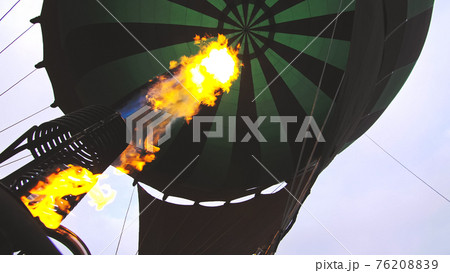 Adventure on hot air balloon watermelon. Burner directing flame into envelope. The aircraft fly in morning blue sky due to hot air. Adventure on hot air balloon watermelon. Burner directing flame into envelope. The aircraft fly in morning blue sky due to hot air. 76208839