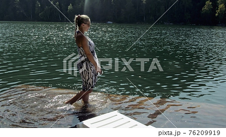 Woman lie on a sunbed in sunglasses and a boho silk shawl. Girl rest on a flood wood underwater pier. The pavement is covered with water in the lake. Woman lie on a sunbed in sunglasses and a boho silk shawl. Girl rest on a flood wood underwater pier. The pavement is covered with water in the lake. 76209919