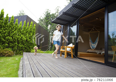 コテージのウッドデッキで犬と遊ぶ女性 コテージのウッドデッキで犬と遊ぶ女性 76211066