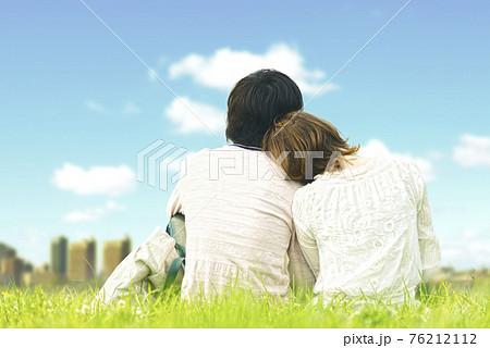 芝生に座り寄り添うカップル 76212112