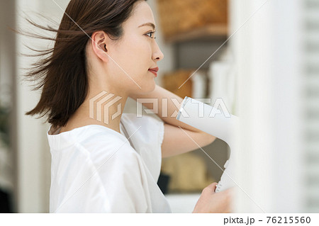 洗面所でドライヤーを使う若い女性 76215560