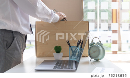 Put the work equipment in the office in a large brown box, Businessmen are keeping work documents and personal belongings due to resignation or being fired, termination of employment. 76218656