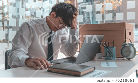 Businessman held his temple with his hand and had a brown document box beside it, Businessmen hand in resignation papers and packing office supplies in boxes with regret or disappointment. 76218661