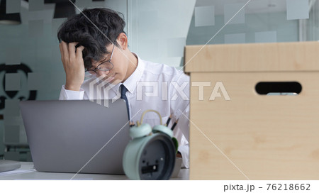 Businessman held his temple with his hand and had a brown document box beside it, Businessmen hand in resignation papers and packing office supplies in boxes with regret or disappointment. Businessman held his temple with his hand and had a brown document box beside it, Businessmen hand in resignation papers and packing office supplies in boxes with regret or disappointment. 76218662