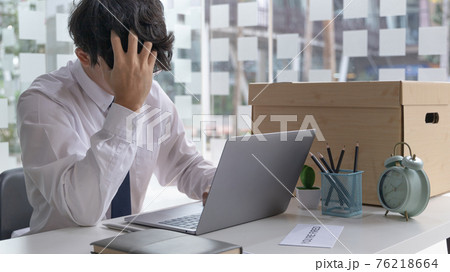 Businessman held his temple with his hand and had a brown document box beside it, Businessmen hand in resignation papers and packing office supplies in boxes with regret or disappointment. 76218664