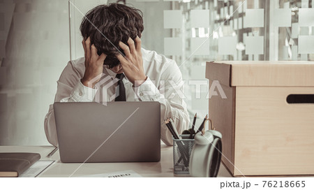 Businessman held his temple with his hand and had a brown document box beside it, Businessmen hand in resignation papers and packing office supplies in boxes with regret or disappointment. 76218665