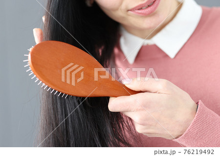 Brunette woman combs her hair with wooden comb 76219492