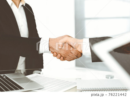 Unknown diverse business people are shaking hands finishing up meeting at the desk in office, close-up. Handshake concept Unknown diverse business people are shaking hands finishing up meeting at the desk in office, close-up. Handshake concept 76221442