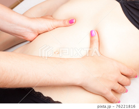 Woman receiving osteopathic treatment of her belly 76221816