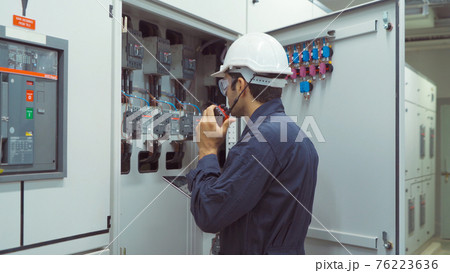 An engineer man or worker, people using a laptop computer, working in electrical room. Power energy motor machinery cabinets in control or server room, operator station network in industry factory. 76223636