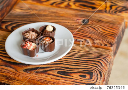 Chocolate candies on a white saucer. 76225346