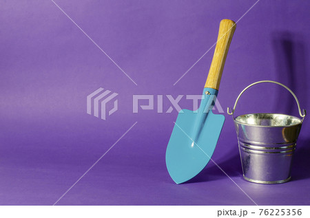 Minimalistic composition with a blue garden shovel and a bucket Minimalistic composition with a blue garden shovel and a bucket 76225356