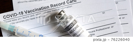 COVID-19 vaccine bottle and syringe are on coronavirus Vaccination Record Card 76226040