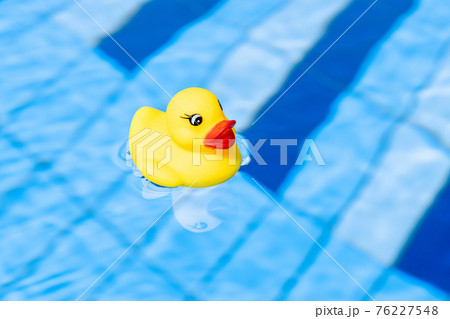 Yellow rubber duck. Funny kids inflatable toy float in blue water of summer pool. Funny bird toy for kids. 76227548