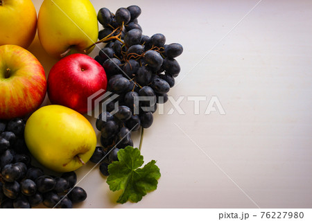 Grapes and apples on a light background with copy space 76227980