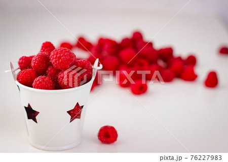 Red ripe and juicy raspberry in a small white bucket with stars 76227983