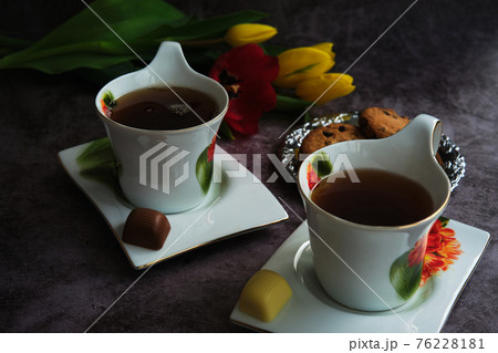 two white cups of tea and yellow and red tulips 76228181
