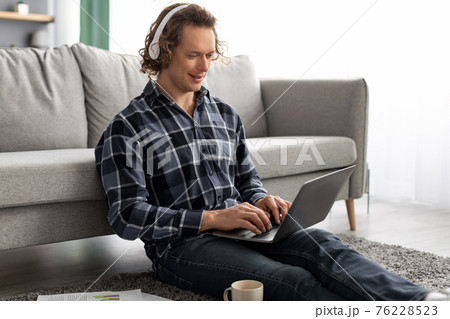 Man In Headphones Using Laptop Working Online Sitting At Home 76228523