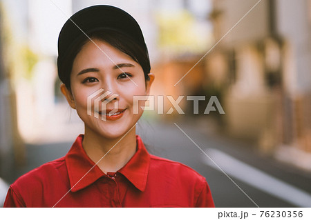 赤いつなぎを着た若い女性 76230356