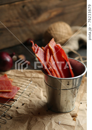 Homemade beef jerky seasoned with garlic, onion, pepper and salt. Jerky in a bucket on a wooden background Homemade beef jerky seasoned with garlic, onion, pepper and salt. Jerky in a bucket on a wooden background 76233679