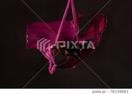 Teen girl performing acrobatic split over head on aerial silks Teen girl performing acrobatic split over head on aerial silks 76236661