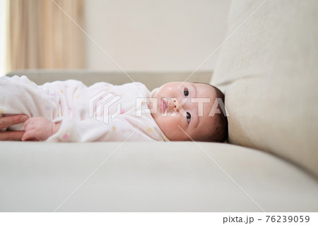 ソファーに寝っ転がるアジア人の赤ちゃん 76239059