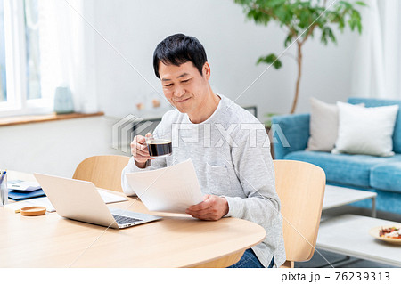 コーヒーを飲みながらテレワークするミドルのビジネスマン 76239313