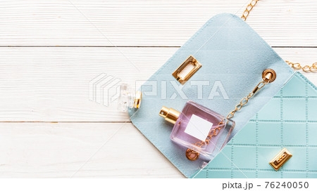 Fashion blue bag woman accessories set. Trendy blue fashion with perfume on wood white background Fashion blue bag woman accessories set. Trendy blue fashion with perfume on wood white background 76240050