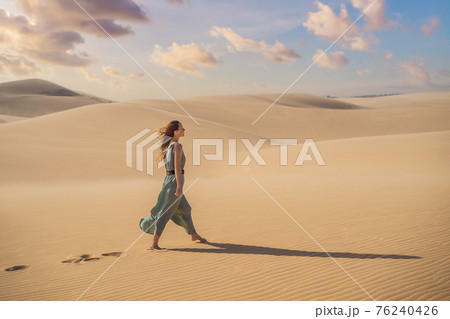 Young beautiful woman traveling in the desert. Sandy dunes and blue sky on sunny summer day. Travel, adventure, freedom concept. Tourism reopens after quarantine COVID 19 Young beautiful woman traveling in the desert. Sandy dunes and blue sky on sunny summer day. Travel, adventure, freedom concept. Tourism reopens after quarantine COVID 19 76240426