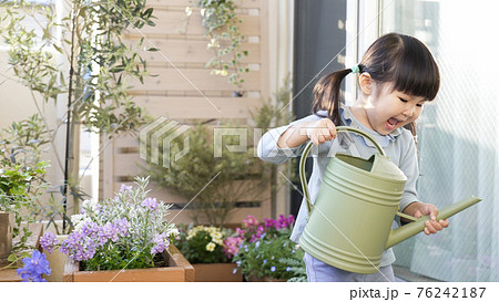 ベランダガーデニングで花に水やりする子供の写真素材