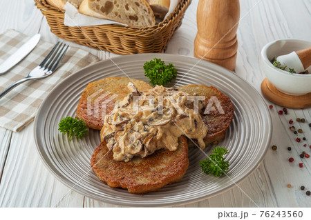 Potato pancakes with sauce and fried onions with parsley 76243560