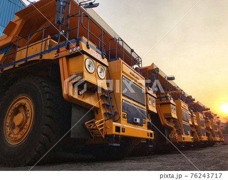 Huge yellow dump trucks stand at sunset 76243717