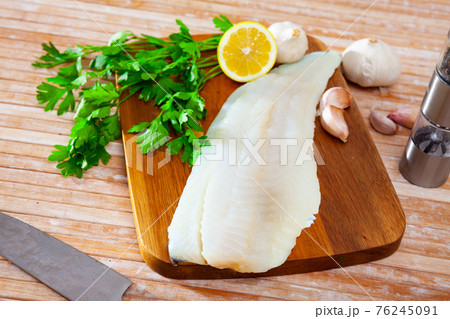 Raw codfish fillet on wooden table with condiments Raw codfish fillet on wooden table with condiments 76245091