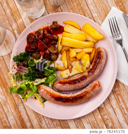 Fried sausages with baked potatoes, mushrooms and lettuce Fried sausages with baked potatoes, mushrooms and lettuce 76245170