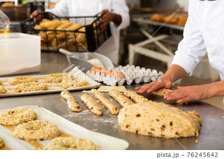 Male baker working with dough shaping baguettes 76245642