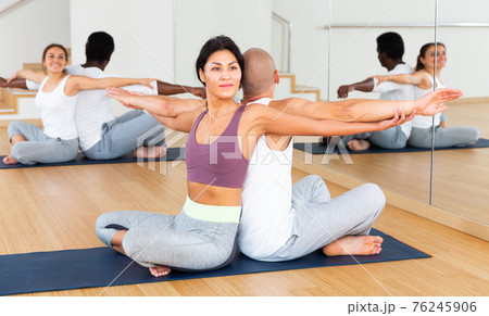 Women and men exercising in pairs during yoga class in fitness center Women and men exercising in pairs during yoga class in fitness center 76245906