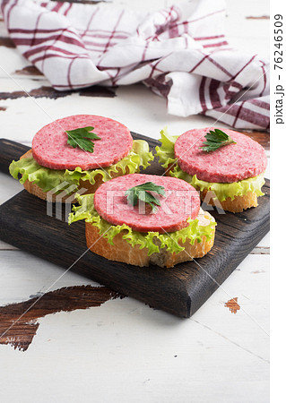 Sandwiches with lettuce leaves and sliced salami sausage on a wooden Board. Copy space 76246509