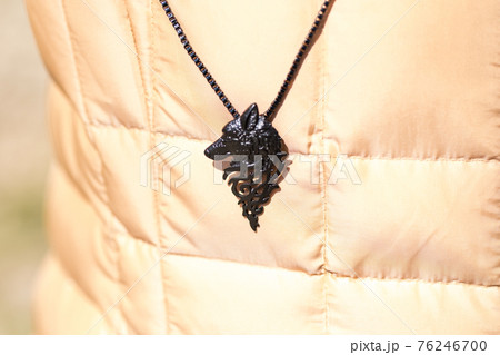Pendant wolf head necklace black color shoot outside in a sunny day closeup. Selective Focus 76246700