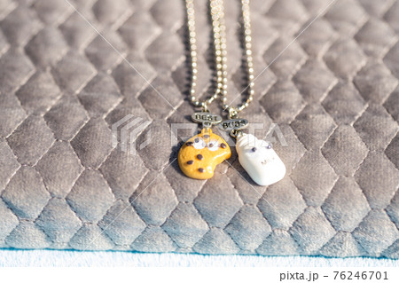 Set of best friends cookie and milk necklace pendant shoot outside in a summer day closeup. Selective Focus 76246701