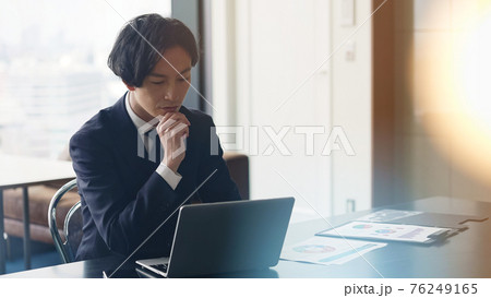 パソコンを見ながら深刻な表情のビジネスマン 76249165