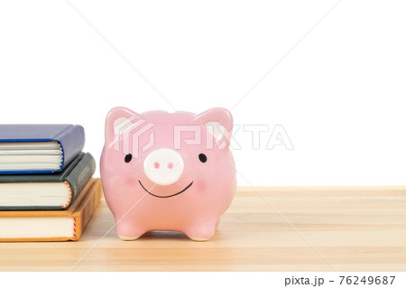 Pink piggy bank on wooden desk with books stack on white background, concept saving for education and scholarship 76249687